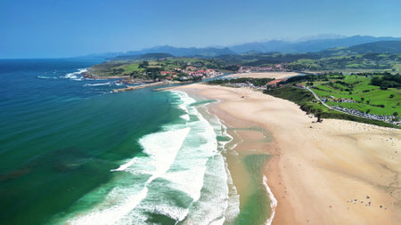 Experience breathtaking aerial footage of a beach with gentle waves and lush green hills surrounding itの写真素材