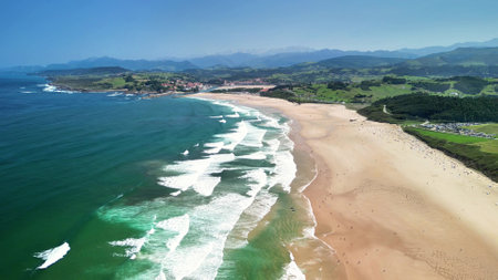 A breathtaking aerial view of a stunning, picturesque beach showcasing gentle waves and lush, green hillsの写真素材