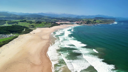 A breathtaking aerial shot beautifully captures the stunning beauty of the beach, complete with waves and lush greeneryの写真素材