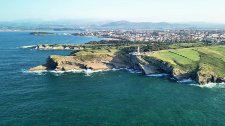 Aerial view reveals dramatic cliffs, a lighthouse, and vast coastal landscapes in a stunning ocean sceneの写真素材