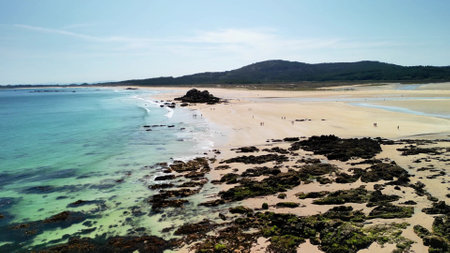 Enjoy a stunning view of a serene beach with crystal clear waters, soft sands, and beautiful surrounding landscapesの写真素材