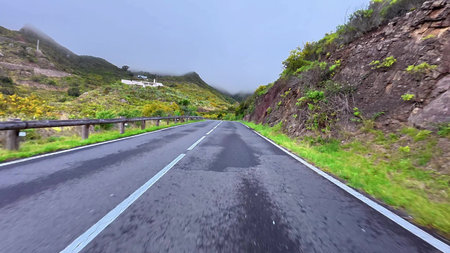 Experience a breathtaking view of a winding road embraced by vibrant landscapes and dramatic skies...
