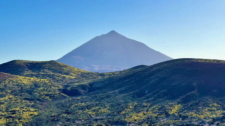 Behold the breathtaking and stunning view of a magnificent volcano, surrounded by lush greenery beneath clear skiesの写真素材