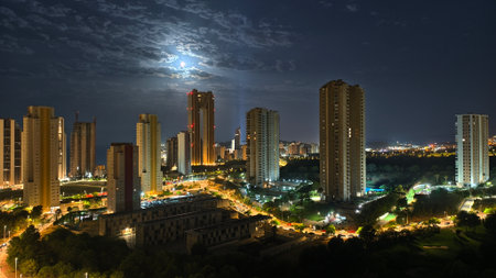 Night cityscape with urban buildings and full moonの写真素材