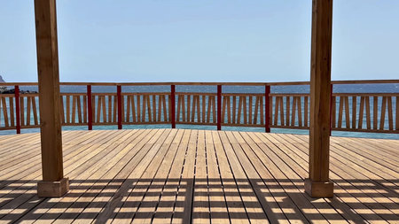 Behold the breathtaking view of the vast ocean from a charming wooden deck gazebo beautifully...