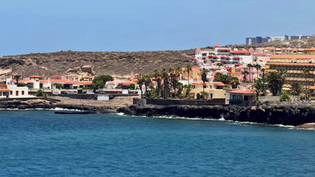 A breathtaking coastal landscape that showcases vibrant homes nestled by the sea alongside rugged rocky cliffsの写真素材