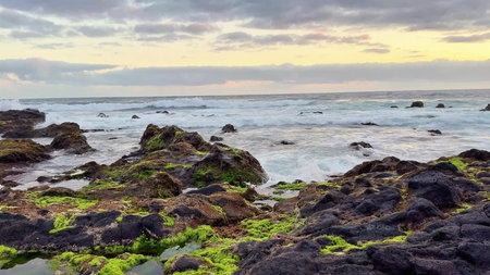 A peaceful and tranquil view of rocky shores and gentle waves gently lapping under a beautiful sunset skyの写真素材