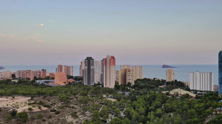 A breathtaking and stunning view of a coastal city featuring modern architecture set by the ocean during sunsetの写真素材