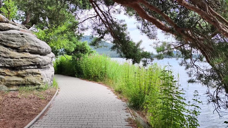 Discover a beautiful and serene walking path situated by the tranquil water, surrounded by vibrant...