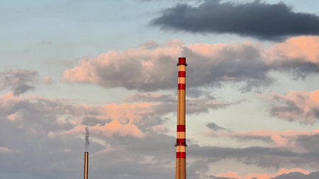 Stunning industrial chimneys are silhouetted against a vibrant sunset with dynamic cloud formations