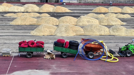 Equipment and carts ready for transporting materials amidst piles of drying substance on a facility ground.の写真素材