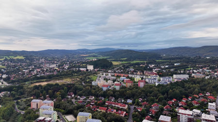 Stunning and breathtaking aerial imagery of a vibrant cityscape nestled amidst lush green hills and cloudy skiesの写真素材