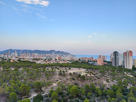 Witness the breathtaking panorama of a stunning city perfectly nestled between lush hills and the sea at sunsetの写真素材