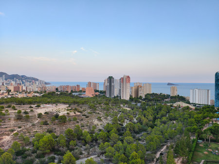 A stunning view of a coastal city featuring vibrant greenery and modern skyscrapers against the sea.の写真素材