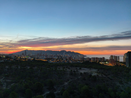 A breathtaking and stunning view of a beautiful sunset illuminating the majestic mountains and city skylineの写真素材