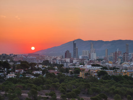 The breathtaking view of a stunning sunset illuminating a picturesque city skyline with majestic mountains at duskの写真素材