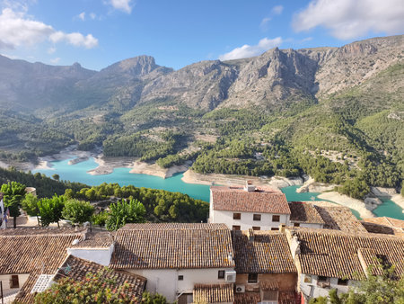A breathtaking landscape showcasing a serene lake, majestic mountains, and charming village homes nestled nearbyの写真素材