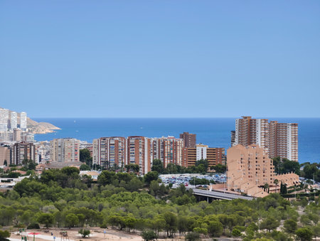 A stunning coastal view with modern buildings along the beach, surrounded by vibrant, lush greeneryの写真素材