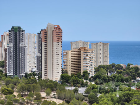 Enjoy a breathtaking view of modern highrises along a picturesque coastline, surrounded by vibrant greeneryの写真素材