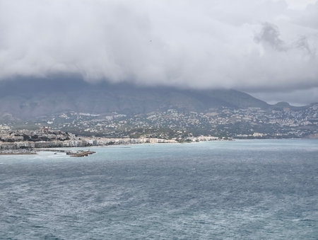 A serene and tranquil scene showcasing beautiful waters, stunning mountains, and fluffy clouds aboveの写真素材