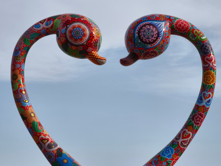 A vibrant sculpture of two stylized birds forming a heart, symbolizing deep love and connection between beingsの写真素材