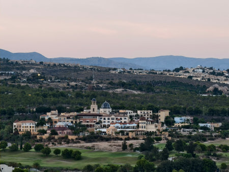 A picturesque town is nestled beautifully in lush greenery and rolling hills as the dusk settles inの写真素材