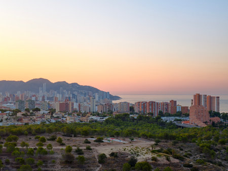 Enjoy a stunning view of a coastal city at sunset, beautifully showcasing the blend of vibrant nature and urban lifeの写真素材