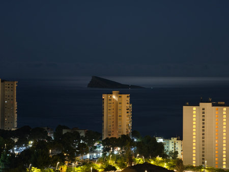 A breathtaking night view of a coastal city skyline filled with glimmering lights and distant sea formationsの写真素材