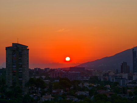A magnificent and stunning sunset beautifully casts vibrant and rich colors over a sprawling urban skylineの写真素材