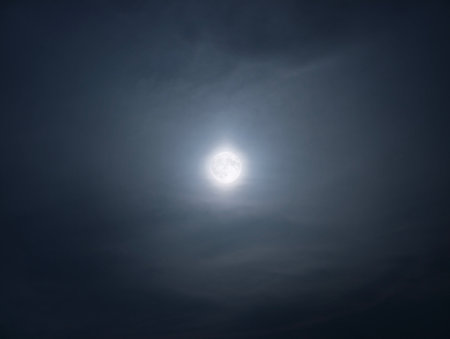 A breathtakingly stunning full moon gracefully surrounded by swirling clouds, evoking a serene and mystical atmosphereの写真素材