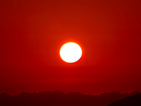 A truly captivating image of the sun beautifully setting, casting a warm, red hue across the vast skyの写真素材