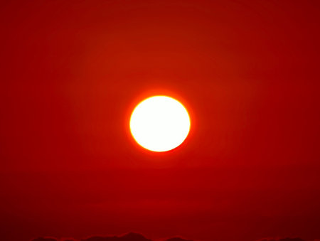 A truly captivating and mesmerizing image of the sun beautifully setting, casting vibrant red hues...