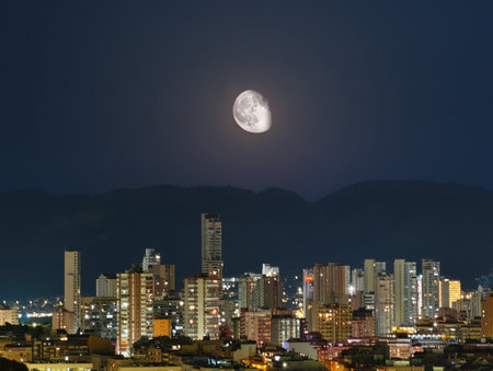 A breathtaking view of a vibrant city skyline, beautifully illuminated by the enchanting moonlight at nightの写真素材