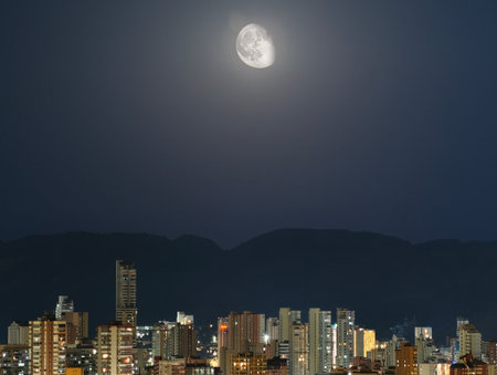 A breathtaking and stunning city skyline beautifully illuminated by a large, bright moon amidst a twilight backdropの写真素材