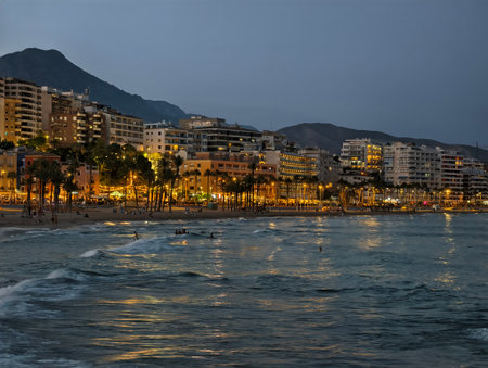 lively seaside promenade at night, bustling waterfront walkway illuminated by hotel lightsの写真素材