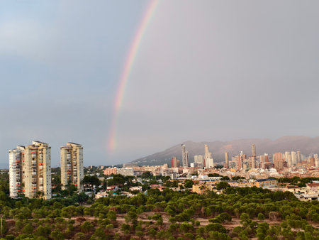 colorful rainbow over cityscape, bright double rainbow arches above scenic cityの写真素材