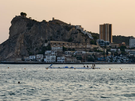 rowing near rocky shoreline at dusk, crew trains at sunset along rugged coastline with rhythmicの写真素材