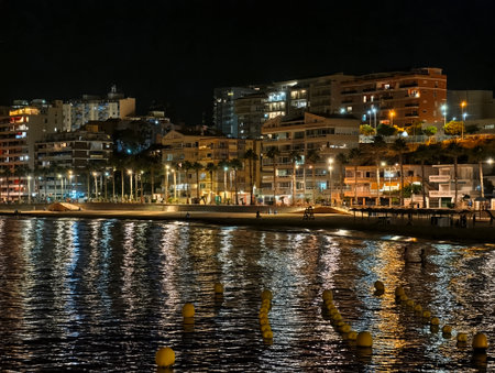 sunset coast stroll, nighttime seaside walkway adorned with palms and shimmering cafe lightsの写真素材