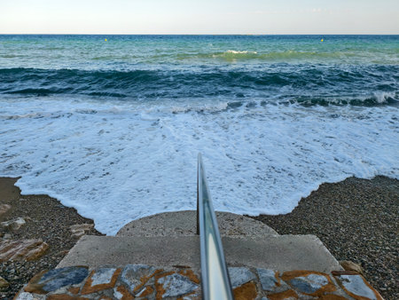 pebble beach and foamy ocean waves, quiet morning at seaside with textured rocks and lapping wavesの写真素材