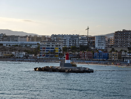 lighthouse guides vessels, beacon on rocky jetty, coastal scene with lighthouse and calm watersの写真素材