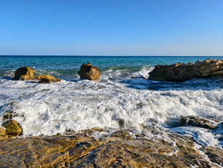 peaceful waves meet rocky coast, gentle surf on rocky shoreline creates perfect scene for travelの写真素材