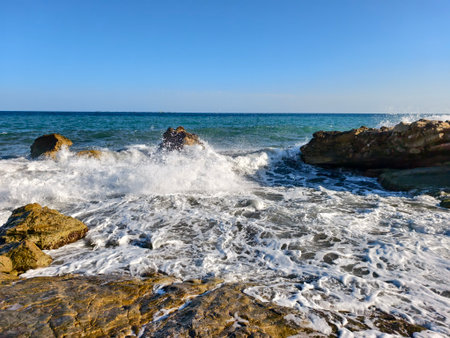 shimmering tide reveals rocky shores, receding tide exposes wet rocks and shimmering reflectionsの写真素材