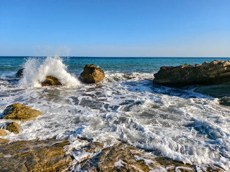 waves crash against submerged rocks, surging waves burst from submerged rocks amidst sprayの写真素材