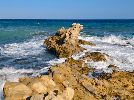 geological landscape with surf, waves carve crevices into layered limestone amid surf and tide poolsの写真素材