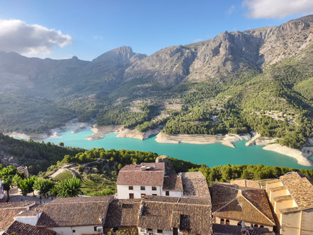 sunlit reservoir over rooftops, panoramic shot of turquoise reservoir with surrounding landscapeの写真素材
