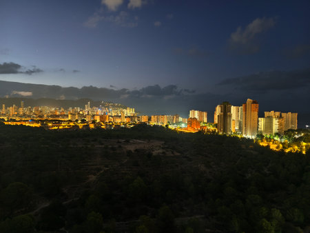 sunset over city and forest view, nighttime urban cityscape with sunset and illuminated treesの写真素材