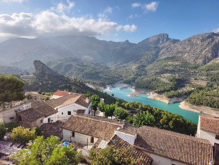 stunning aerial view showcasing mountain village cascading down hillside beside shimmering turquoiseの写真素材