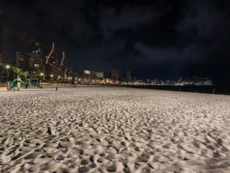 city lights on tranquil beach, serene evening stroll across sandy area illuminated by city lightsの写真素材