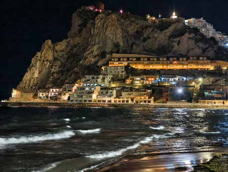 coastal night photography, nighttime coastal village illuminated by warm lights and crashing wavesの写真素材