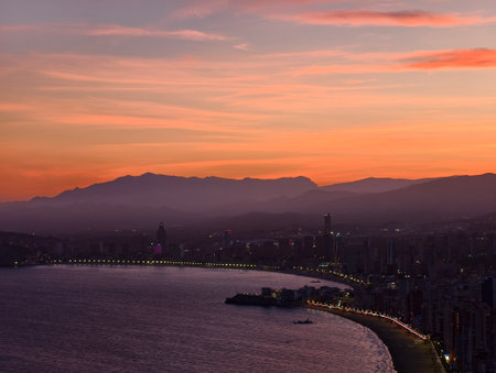 sunset illuminates coast and bay, dramatic sunset casts orangepink hues over scenic waterfront viewの写真素材